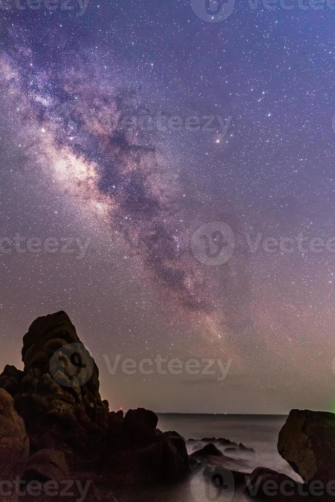 o céu estrelado à beira do mar e a via láctea foto