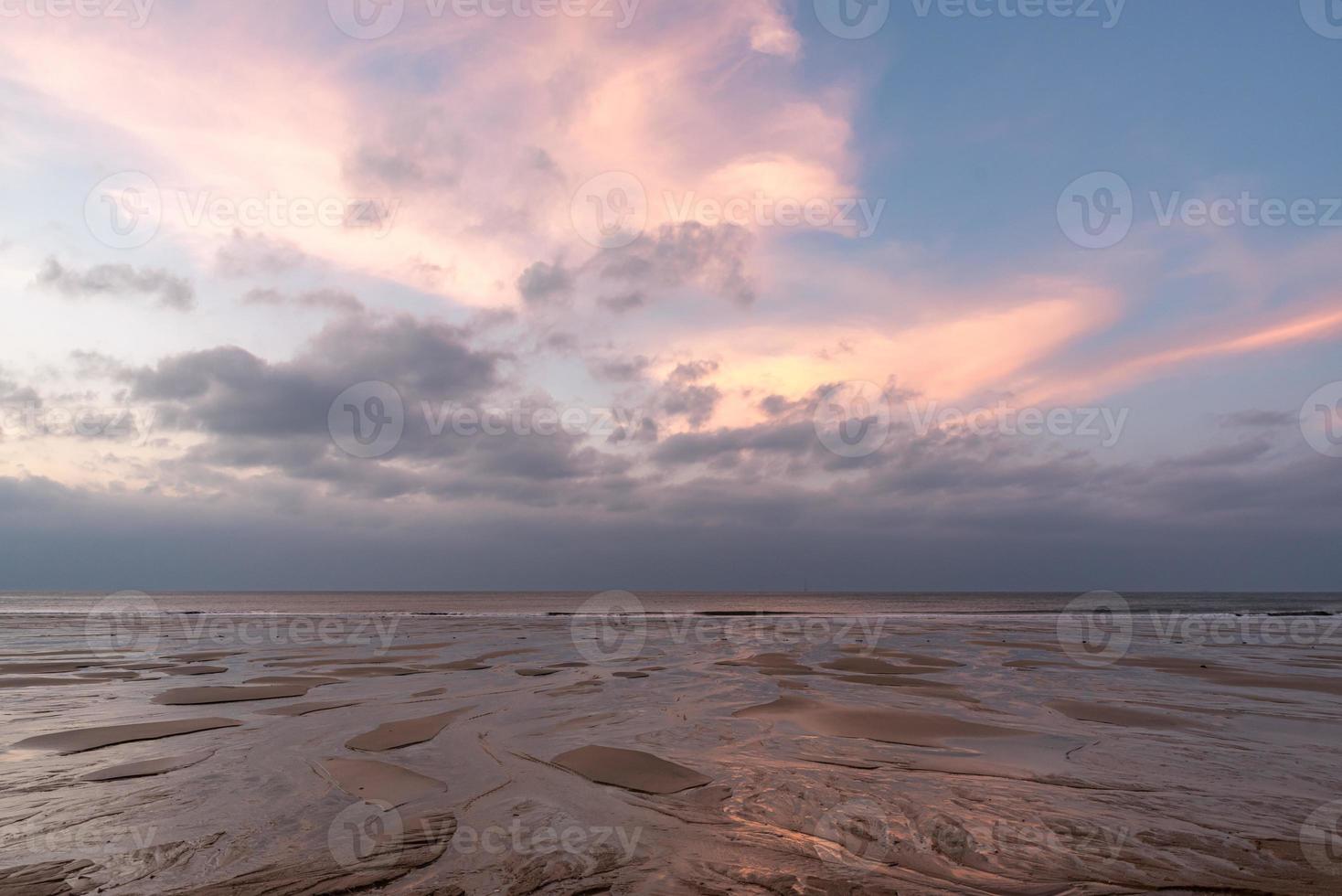 no início da manhã junto ao mar, o céu e a praia estão ligeiramente vermelhos foto