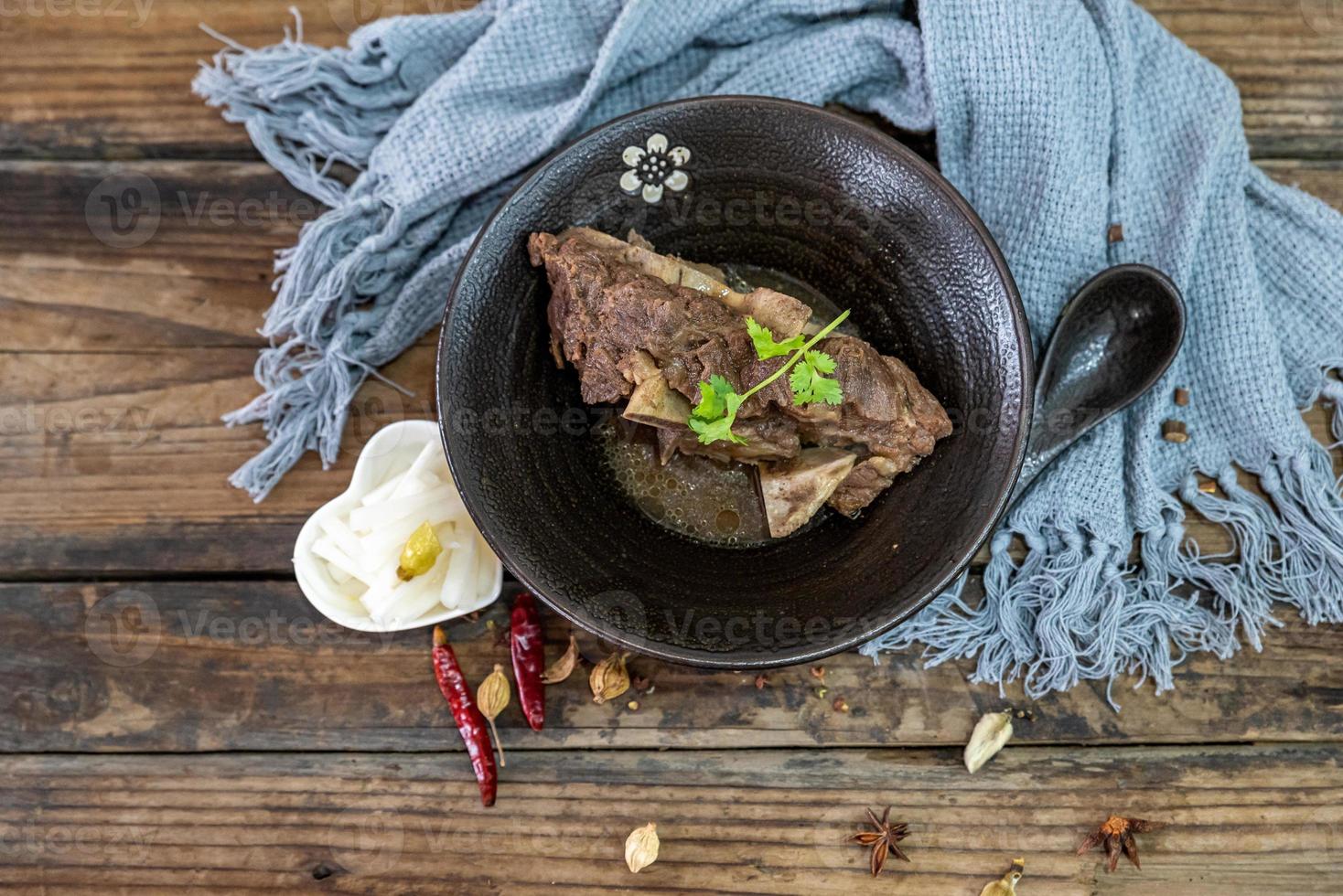 a comida feita de carne bovina está na tigela sobre a toalha da mesa de madeira foto