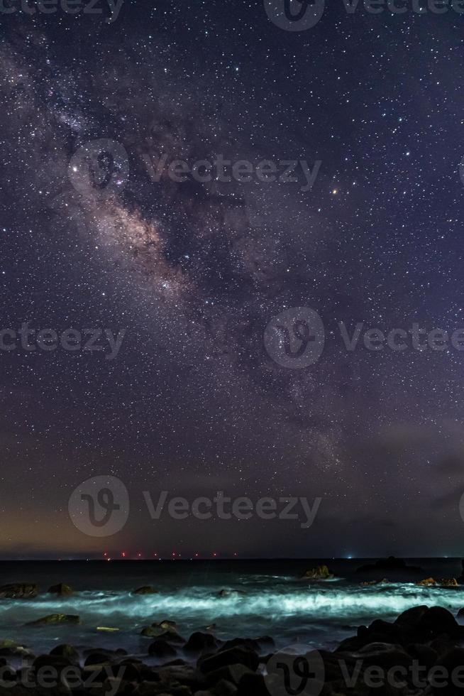 o céu estrelado à beira do mar e a via láctea foto