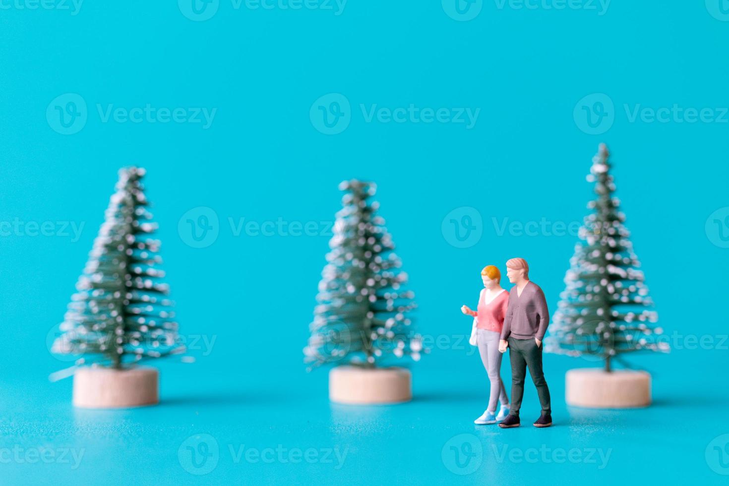 pessoas em miniatura, casal apaixonado em pé ao lado de uma árvore de natal foto
