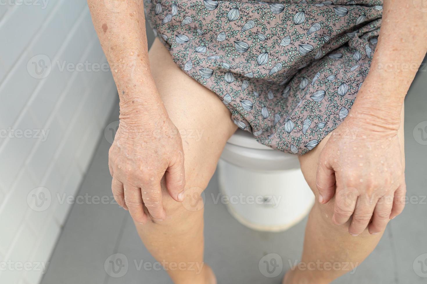 paciente asiático sênior ou idosa senhora sentada no autoclismo no banheiro. foto