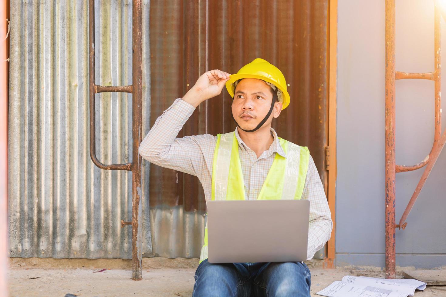 um engenheiro examina a planta baixa do canteiro de obras. foto