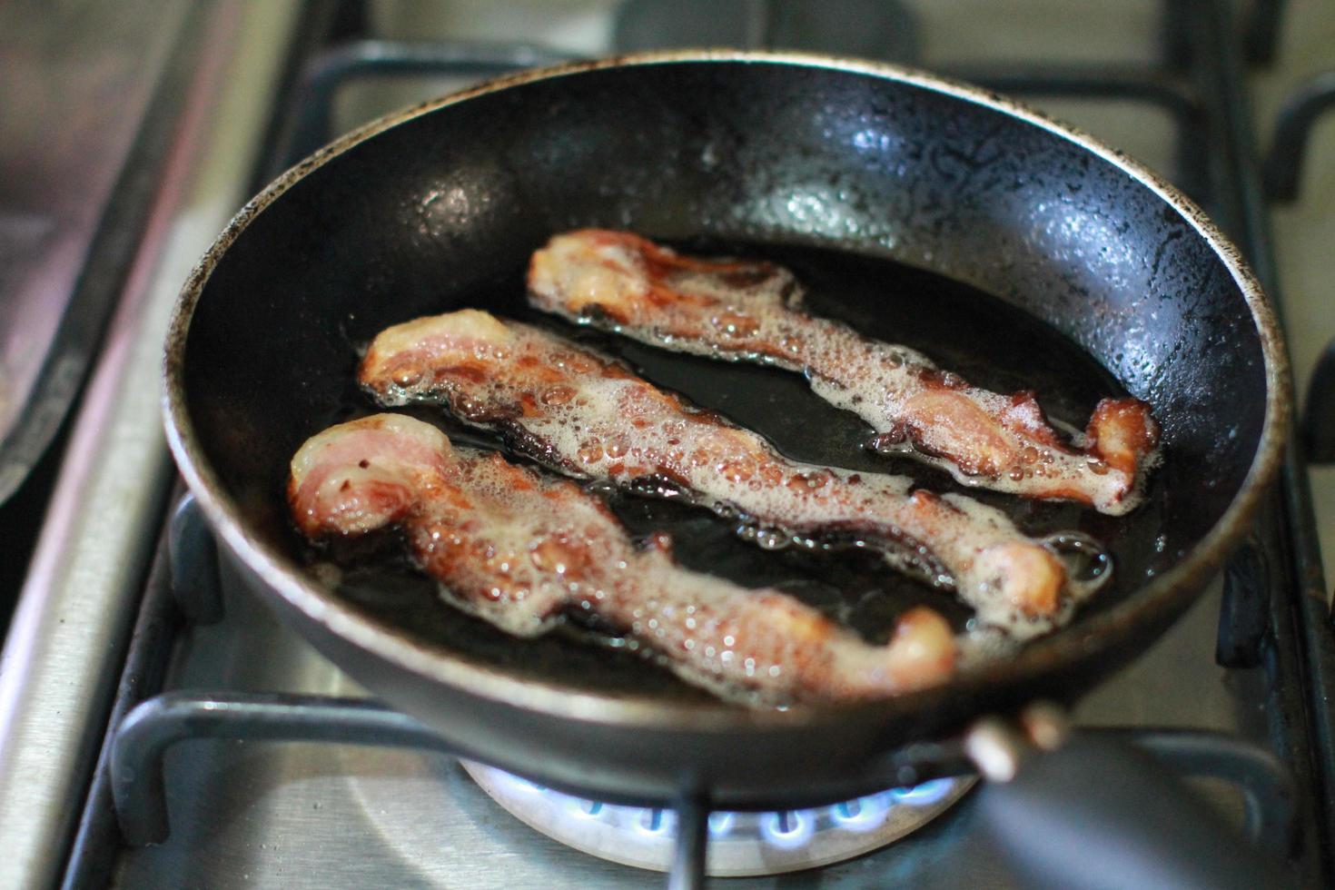 close-up de bacon fritando e cozinhando em uma panela foto