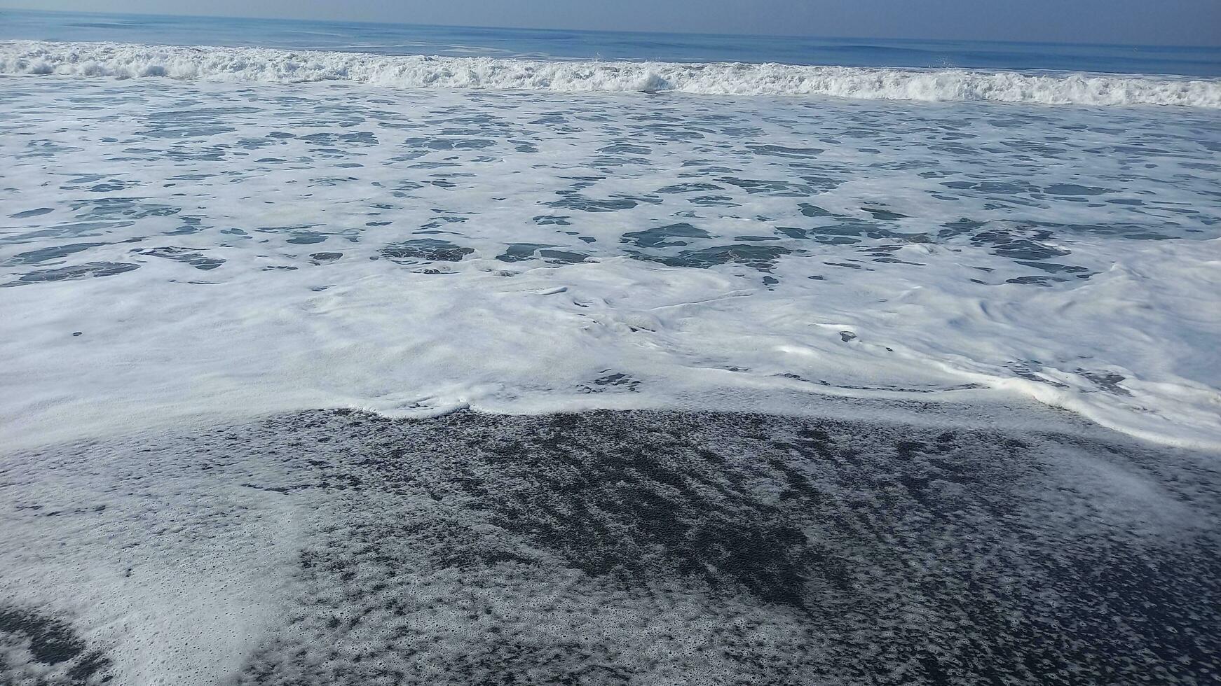 cinzento areia de praia com água onda e fluxo foto