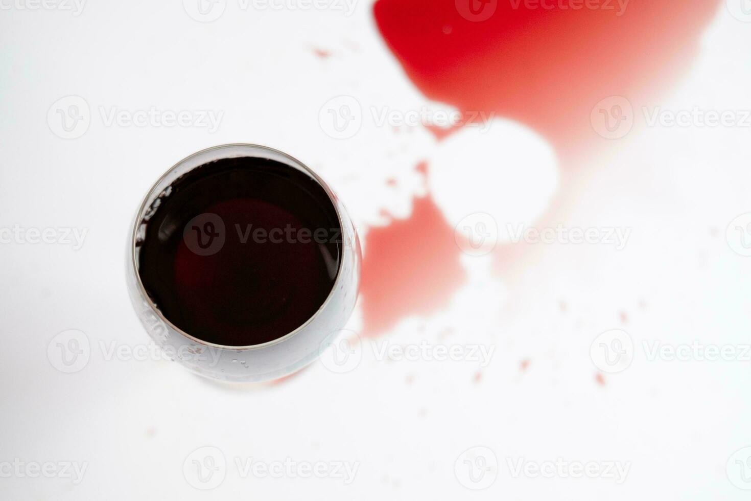 vermelho vinho dentro uma transparente vidro e derramado beber em uma branco fundo foto