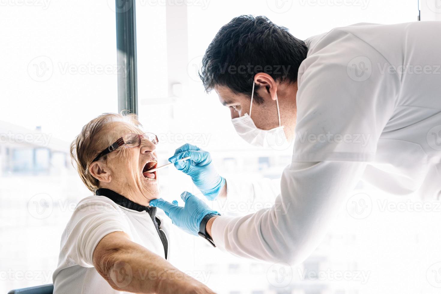 médico fazendo teste de coronavírus de uma mulher idosa foto
