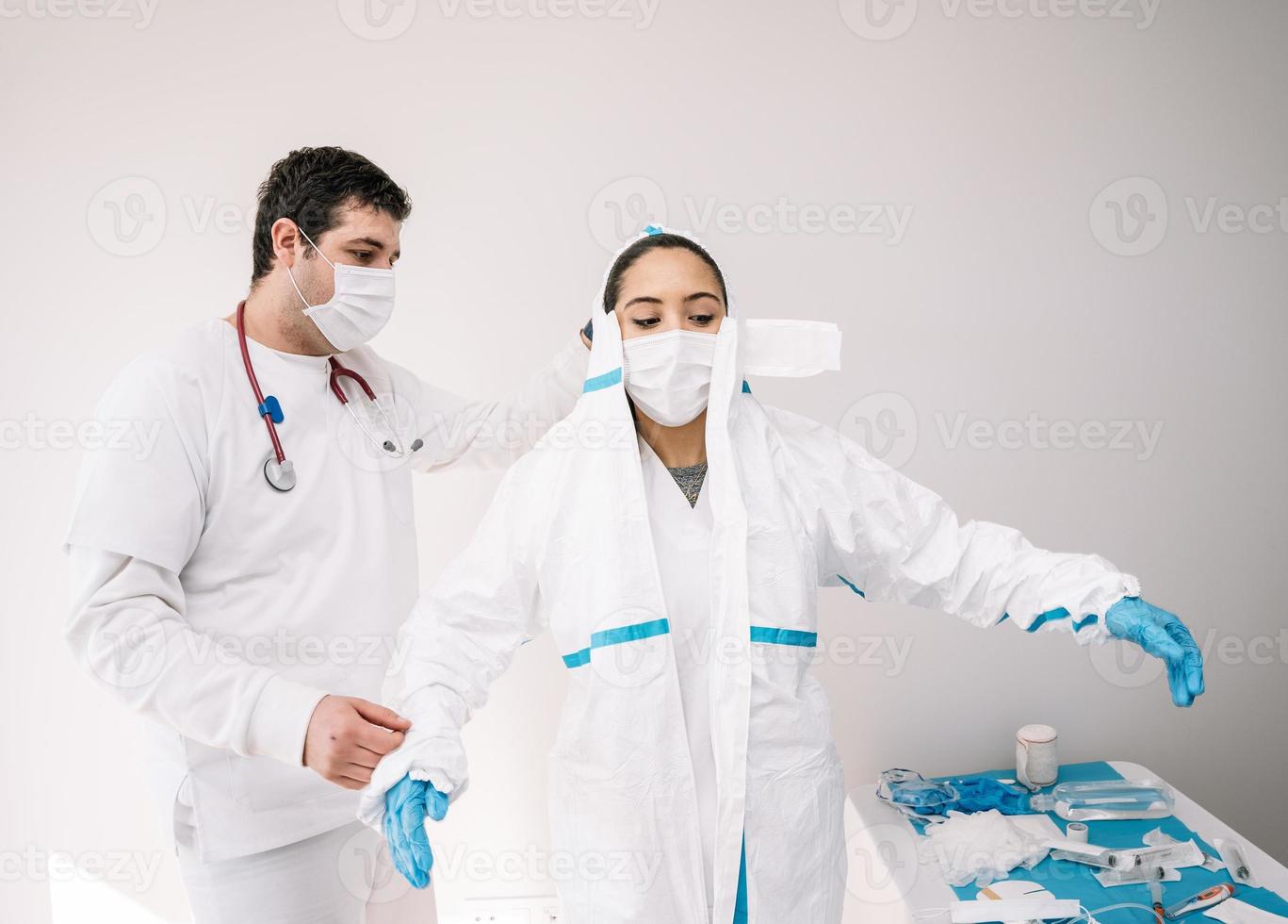 médico ajudando um colega a tirar a fantasia durante a cerimônia foto