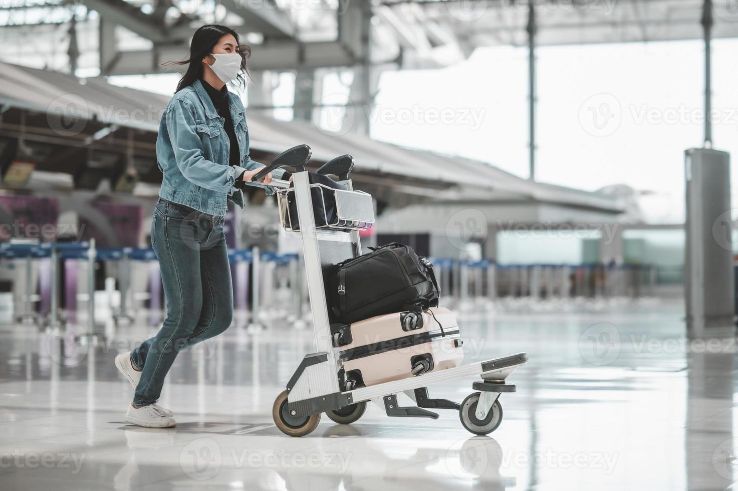 Mulher turista asiática andando com carrinho de bagagem foto