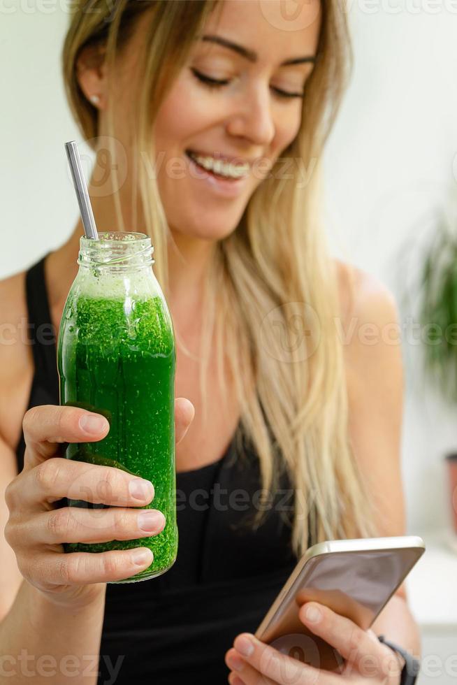 mulher atraente caucasiana segurando uma garrafa de suco verde e rindo. conceito de estilo de vida saudável. foto