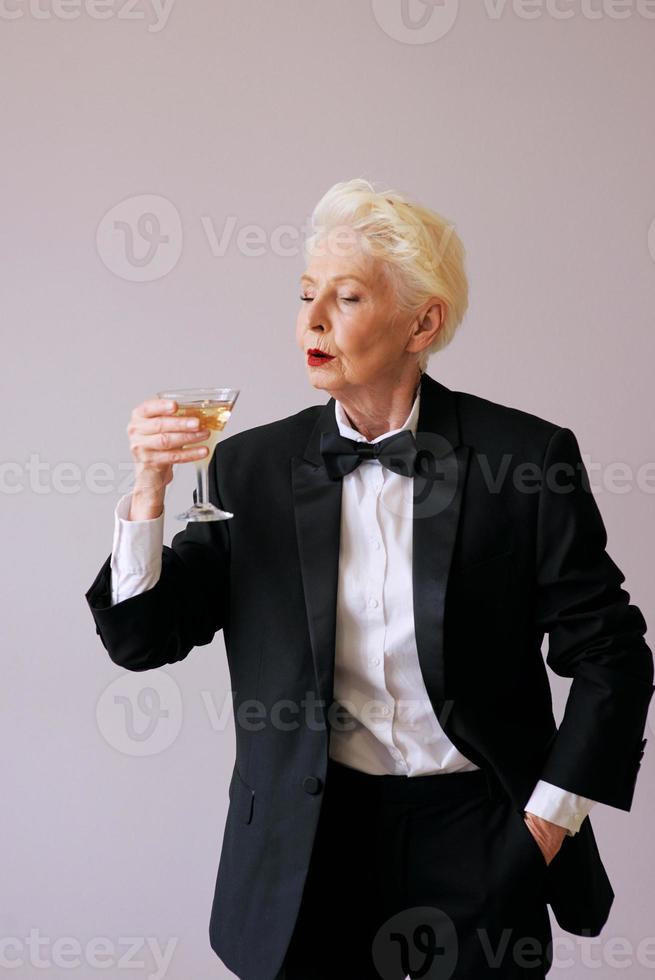 elegante sommelier maduro mulher sênior de smoking com uma taça de vinho espumante. diversão, festa, estilo, estilo de vida, álcool, conceito de celebração foto