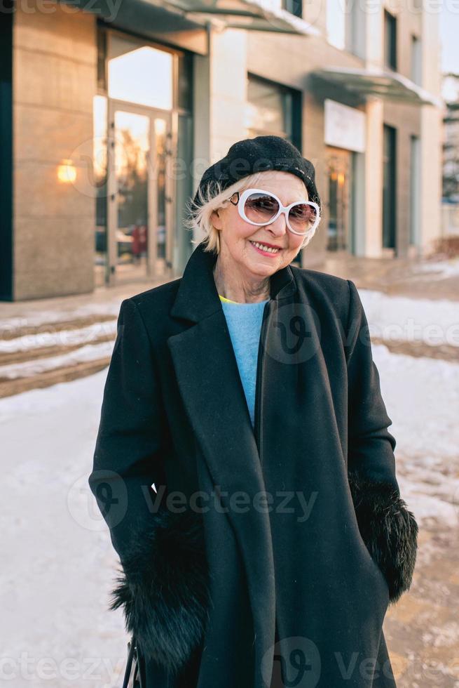 mulher elegante sênior na boina e elegante casaco preto e máscara médica, caminhar ao ar livre. bloqueio, pandemia, conceito de proteção foto