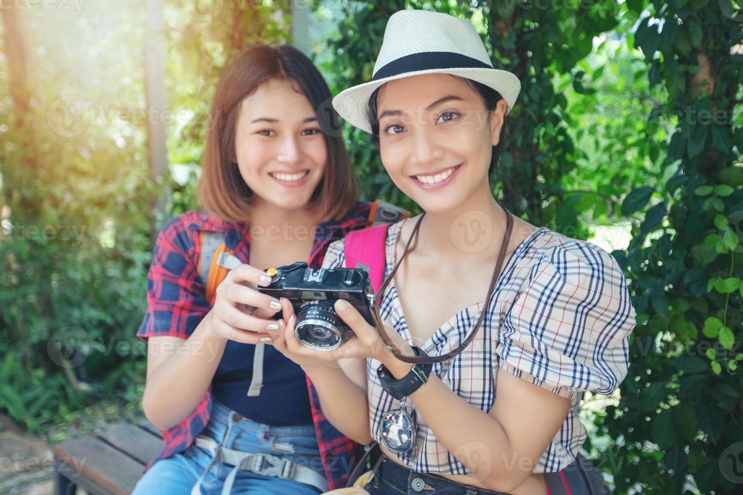 Mochilas de mulheres asiáticas caminhando juntas e felizes estão tirando fotos e olhando fotos, relaxe na viagem do conceito de férias