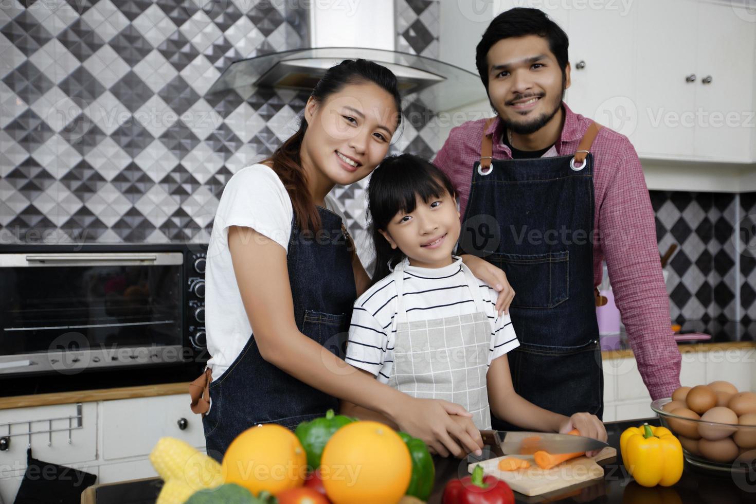 família feliz tem pai, mãe e sua filha cozinhando juntos na cozinha foto