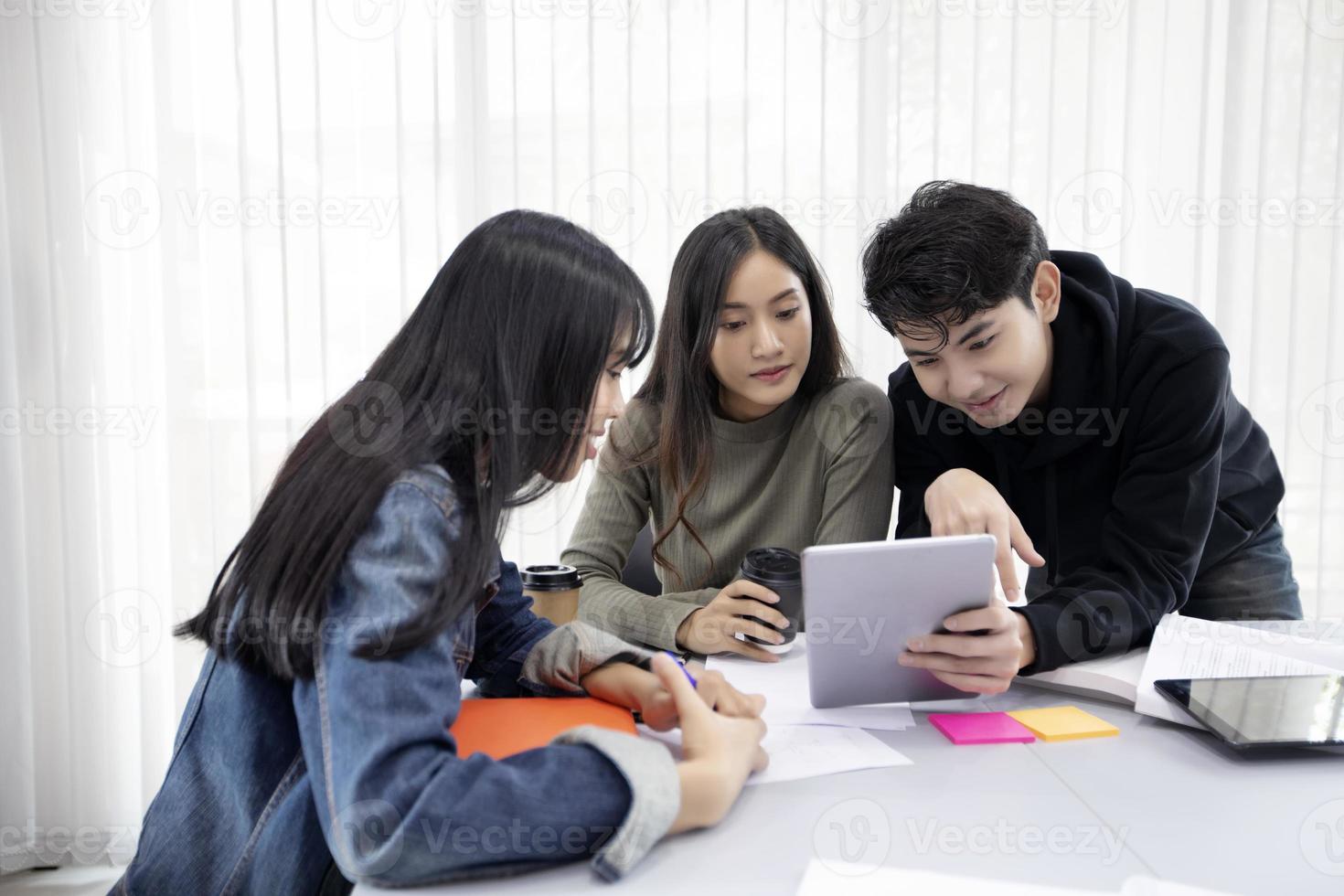 os alunos do grupo sorriem e se divertem e usando o tablet também ajuda a compartilhar ideias no trabalho e no projeto. e também revisar o livro antes do exame foto