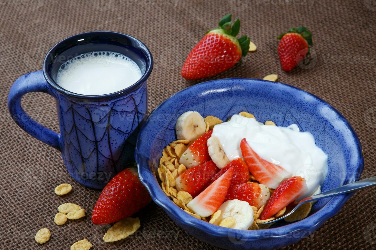 saudável café da manhã. flocos de milho, fresco morangos, banana, iogurte e leite foto