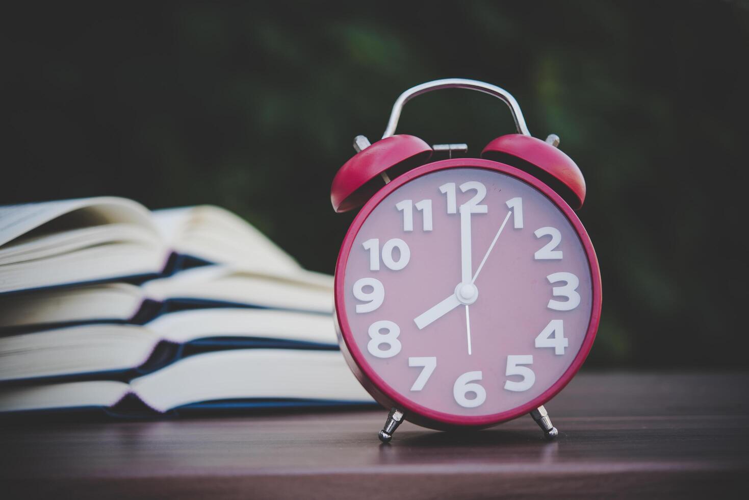 despertador e livros na mesa de madeira com bokeh de fundo. foto