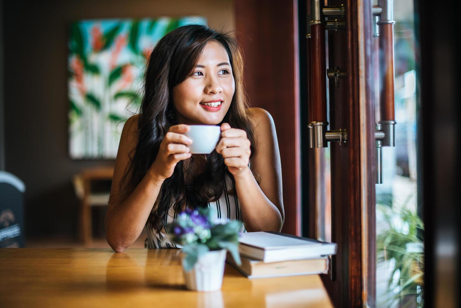 retrato de mulher asiática sorrindo relaxando em uma cafeteria foto