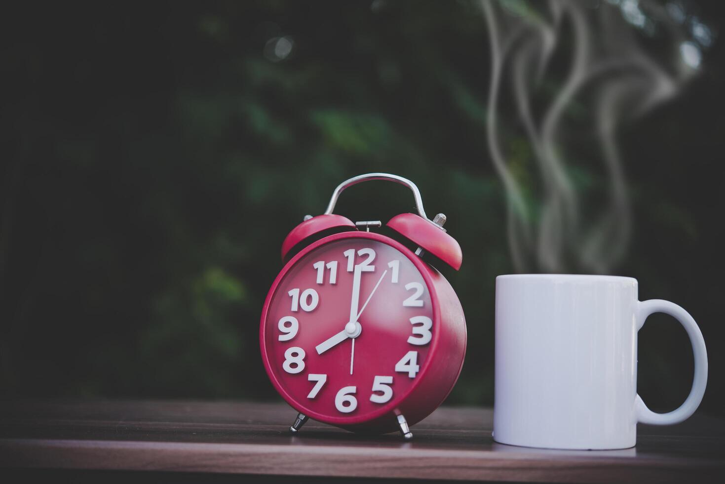 xícara de café e relógio branco na mesa de madeira com bokeh foto