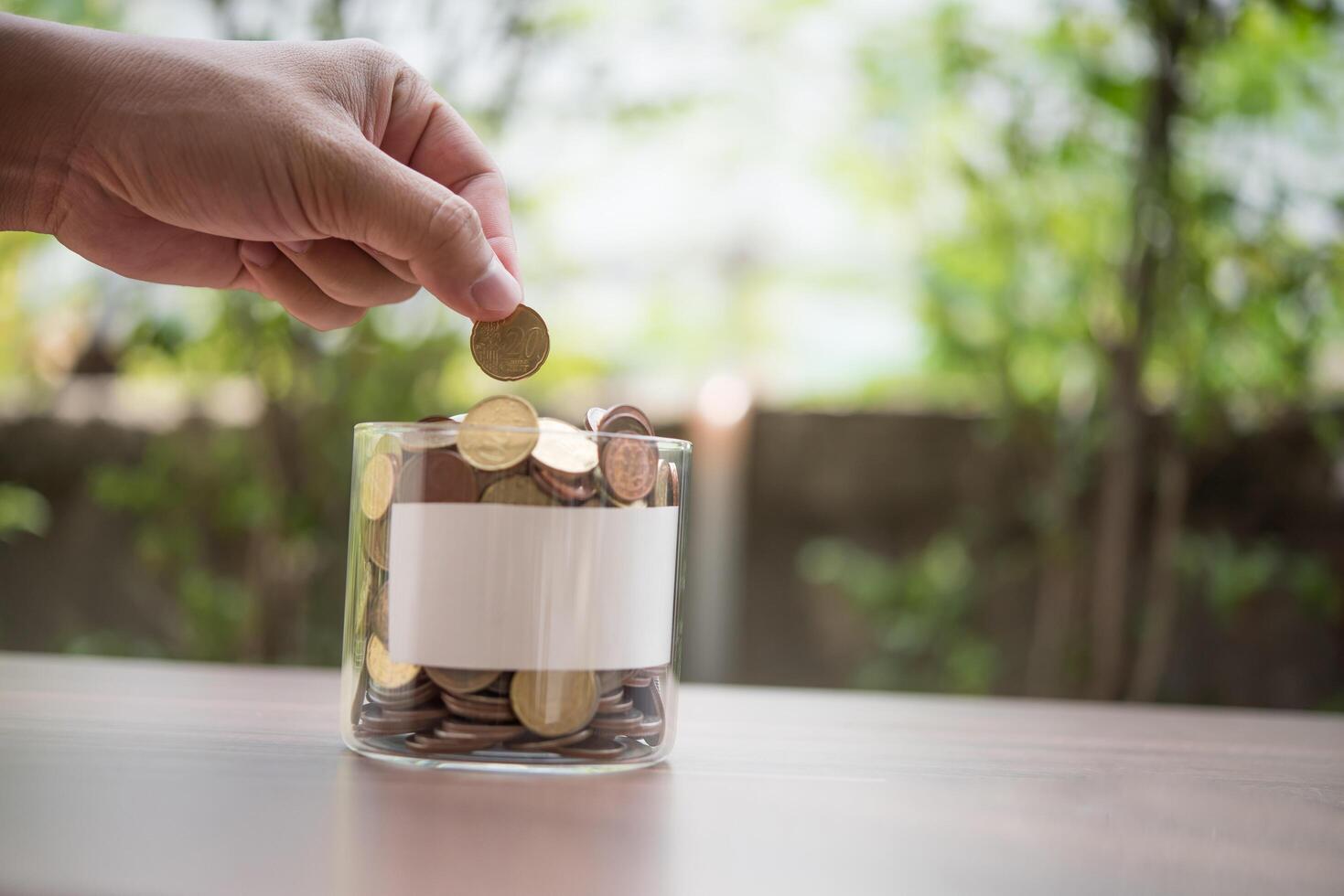 mão colocando moedas na jarra com a etapa da pilha de dinheiro crescendo e economizando dinheiro foto