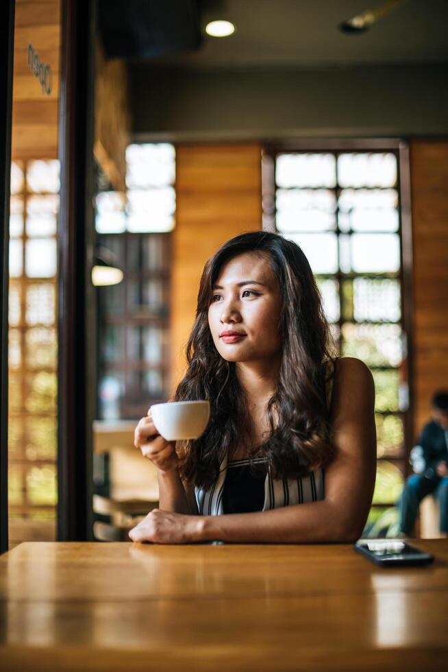 retrato de mulher asiática sorrindo relaxando em uma cafeteria foto