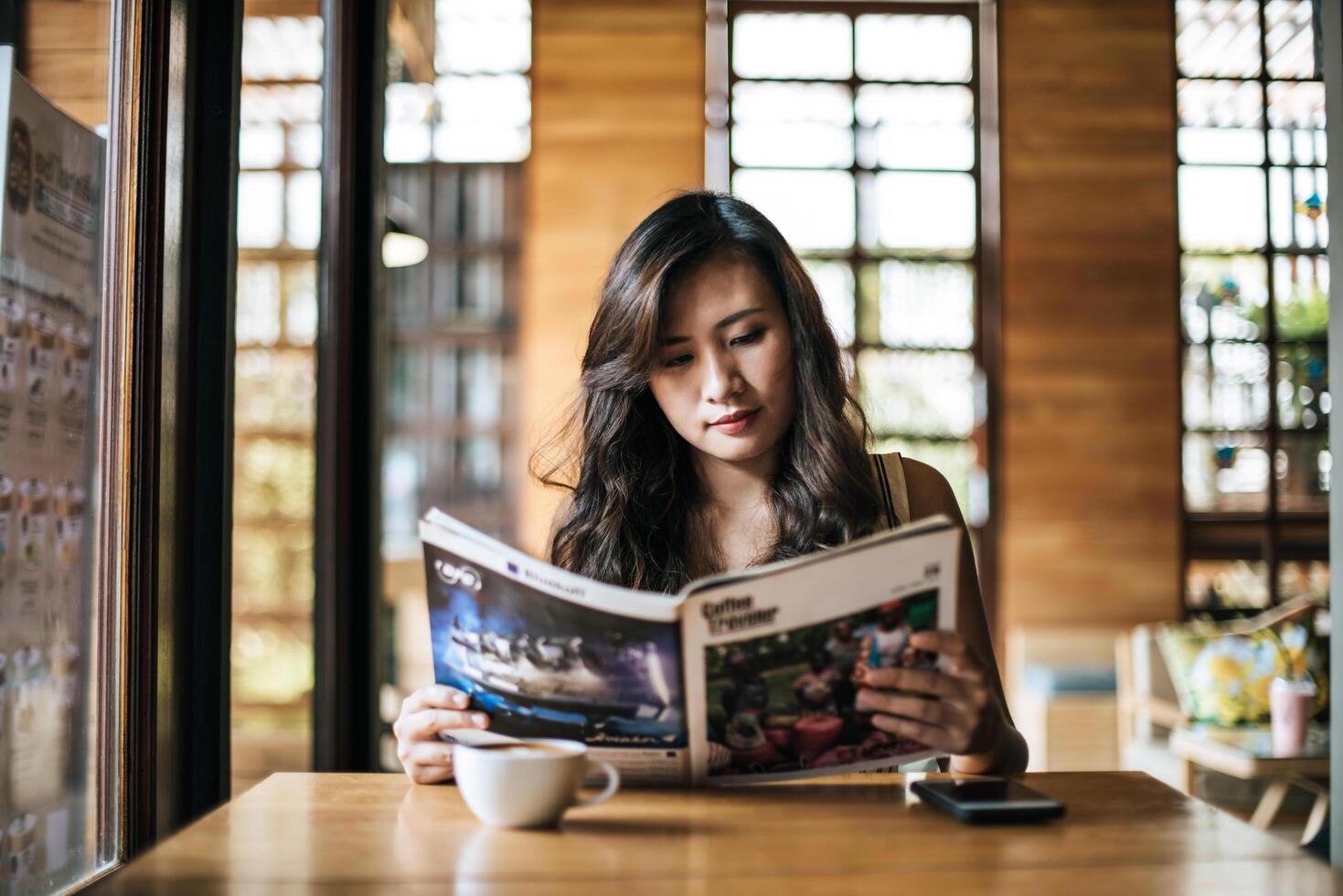 linda mulher lendo revista no café foto