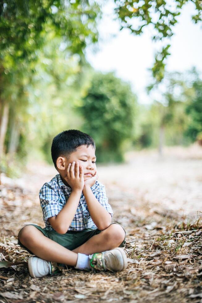 menino feliz sentado e pensando sozinho no parque foto