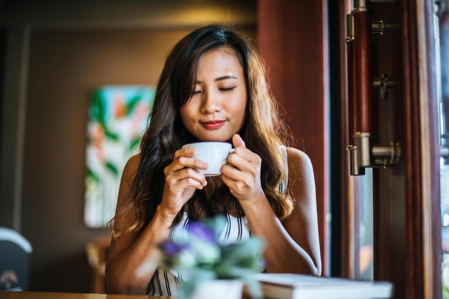 retrato de mulher asiática sorrindo relaxando em uma cafeteria foto