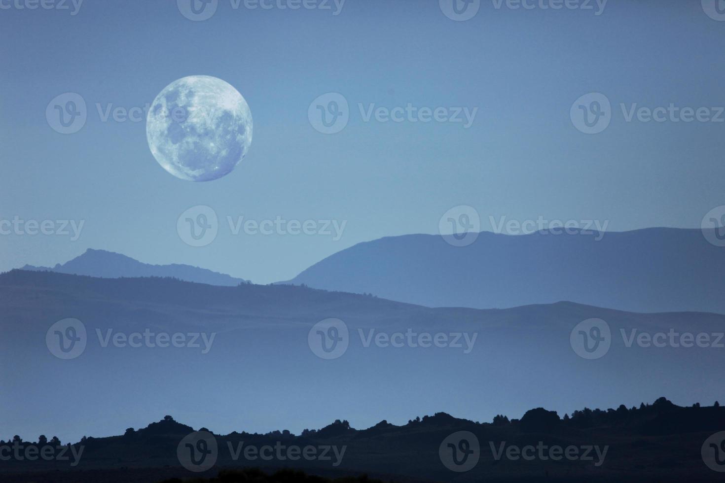 silhuetas de montanhas fantasmagóricas e lua foto