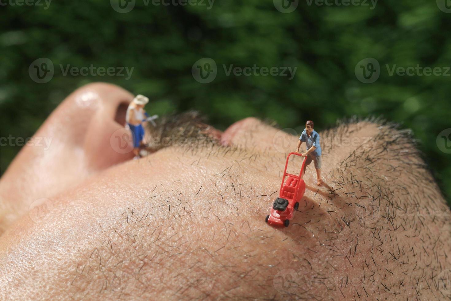 pessoas pequenas cortando o cabelo do rosto de um homem foto