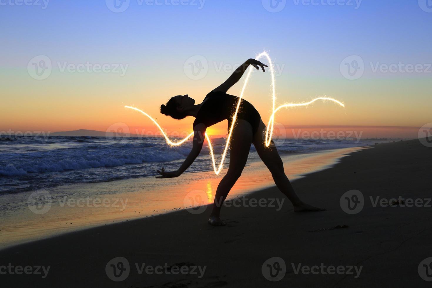 jovem dançarina habilidosa na praia durante o pôr do sol foto