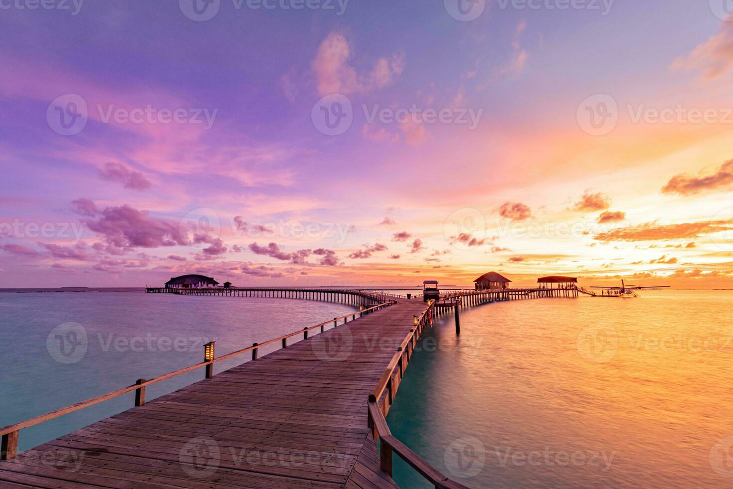 pôr do sol na ilha das Maldivas, resort de villas luxuosas na água e cais de madeira. lindo céu, nuvens e fundo de praia para férias de verão, férias e conceito de viagens foto