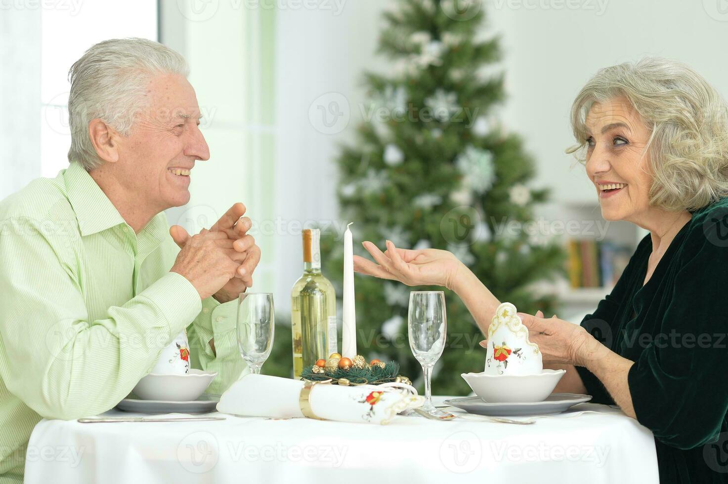 idosos casal às a jantar mesa dando uma Novo anos presente foto