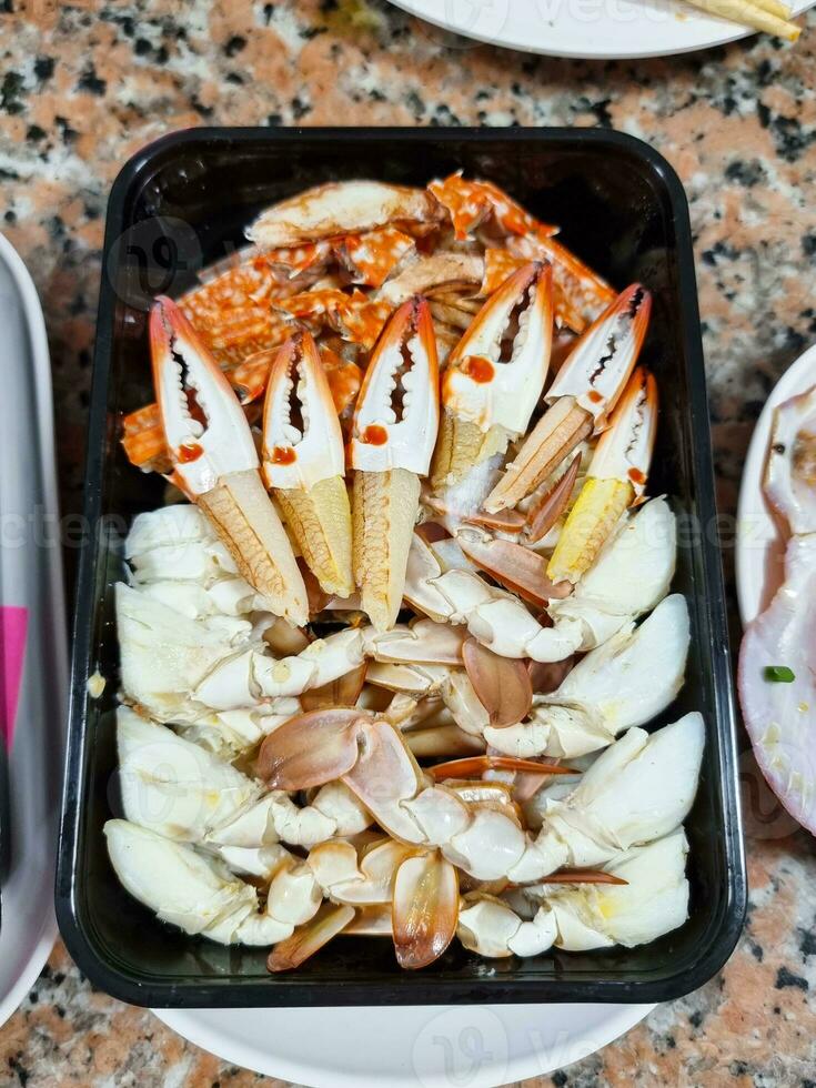 luminária caranguejo carne em Preto plástico prato. quente iniciante Comida ferver fatia frutos do mar dentro restaurante. foto