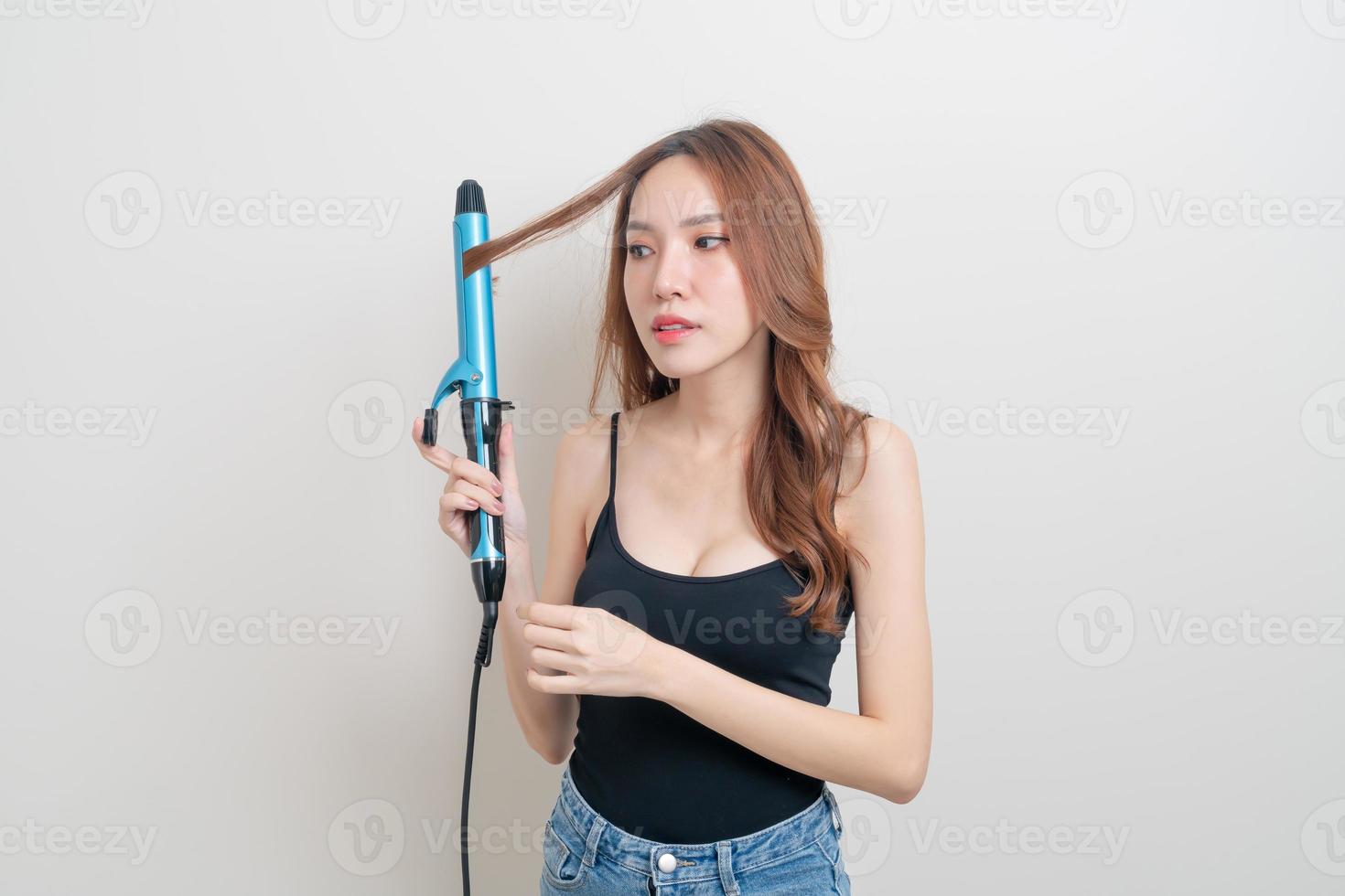 retrato de uma linda mulher asiática usando modelador de cabelo ou modelador de cachos foto