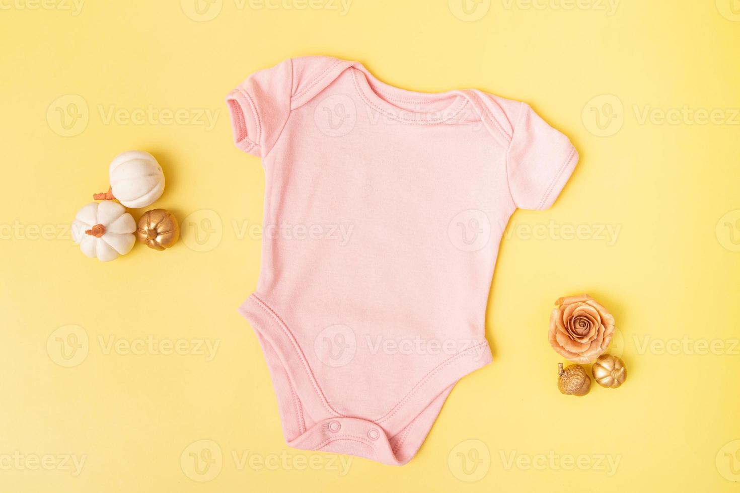 maquete de macacão de bebê com abóboras em fundo amarelo para seu texto ou logotipo na temporada de outono foto