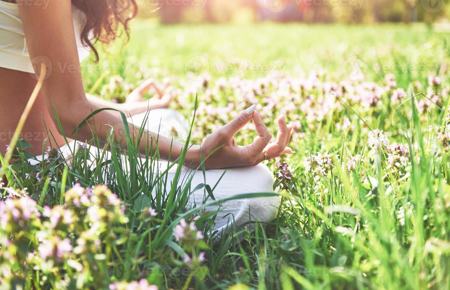 meditação de ioga em um parque na grama é uma mulher saudável em repouso foto