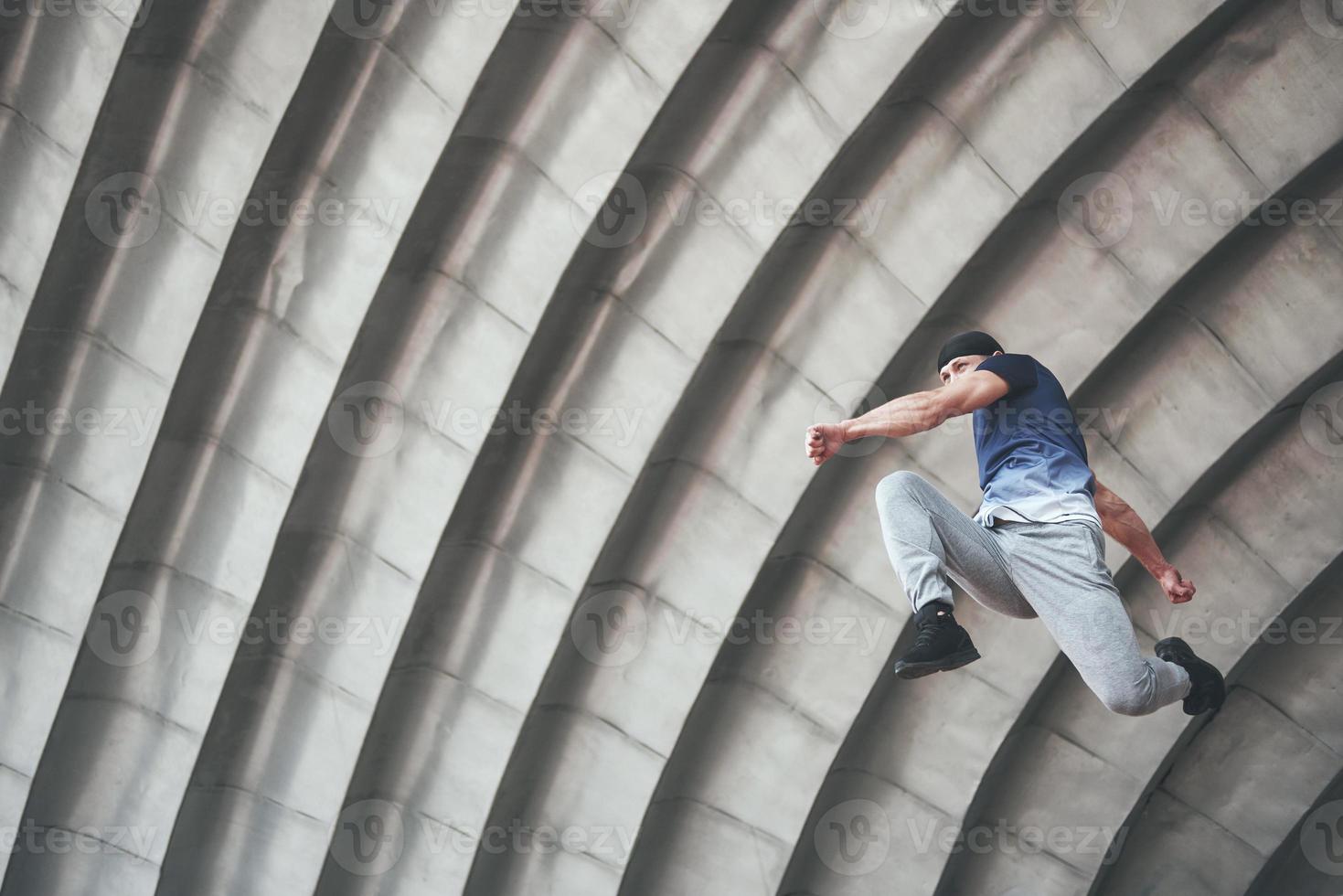 jovem fazendo parkour salto no espaço urbano na cidade ensolarada primavera dia de verão. foto