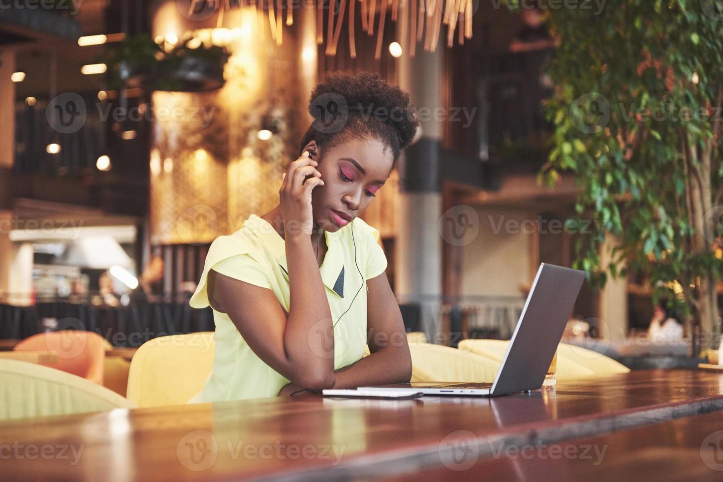 jovem linda mulher de negócios afro-americana falando ao telefone enquanto trabalhava em um café foto