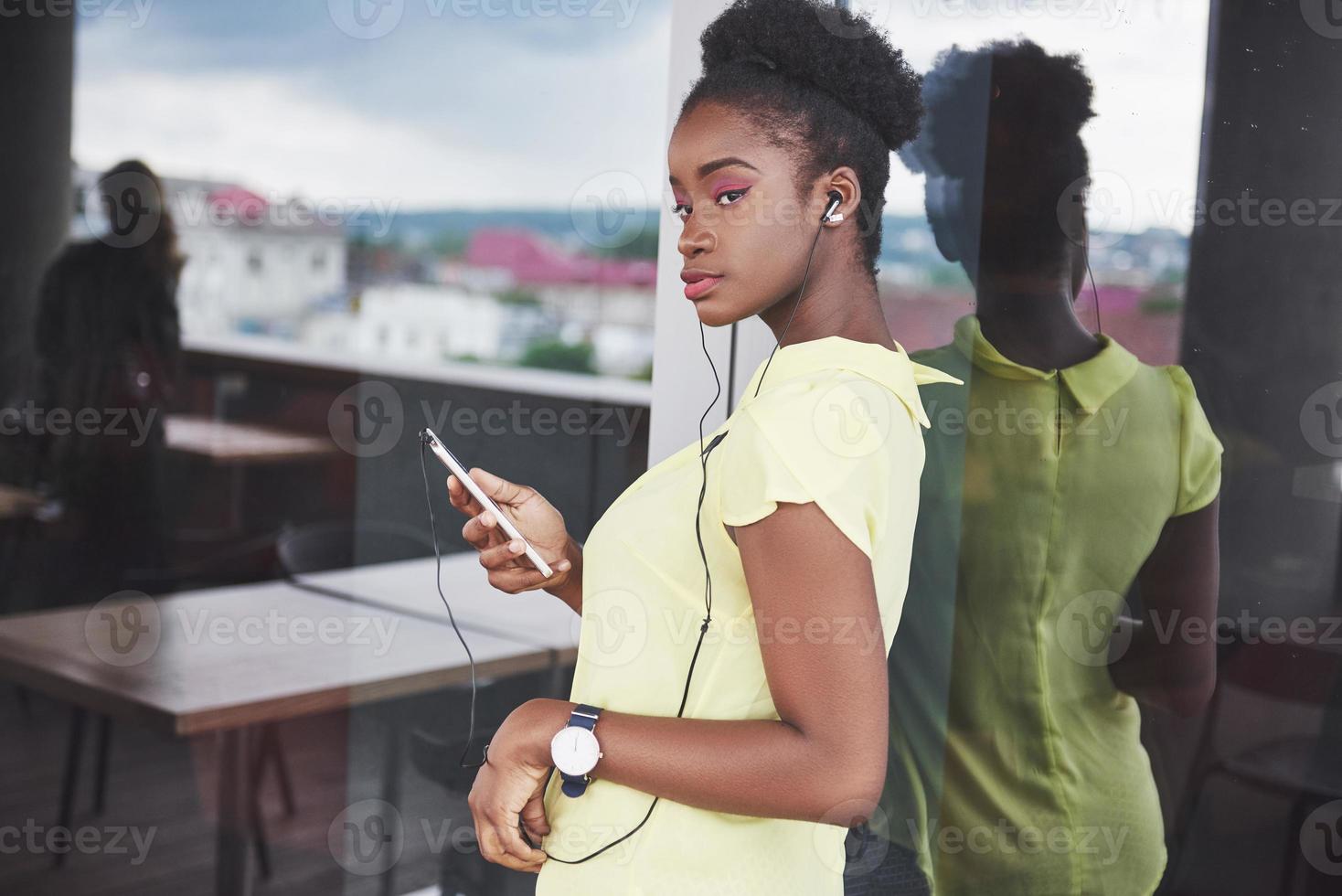 jovem garota afro-americana com cabelo escuro encaracolado pensativa em um café. foto