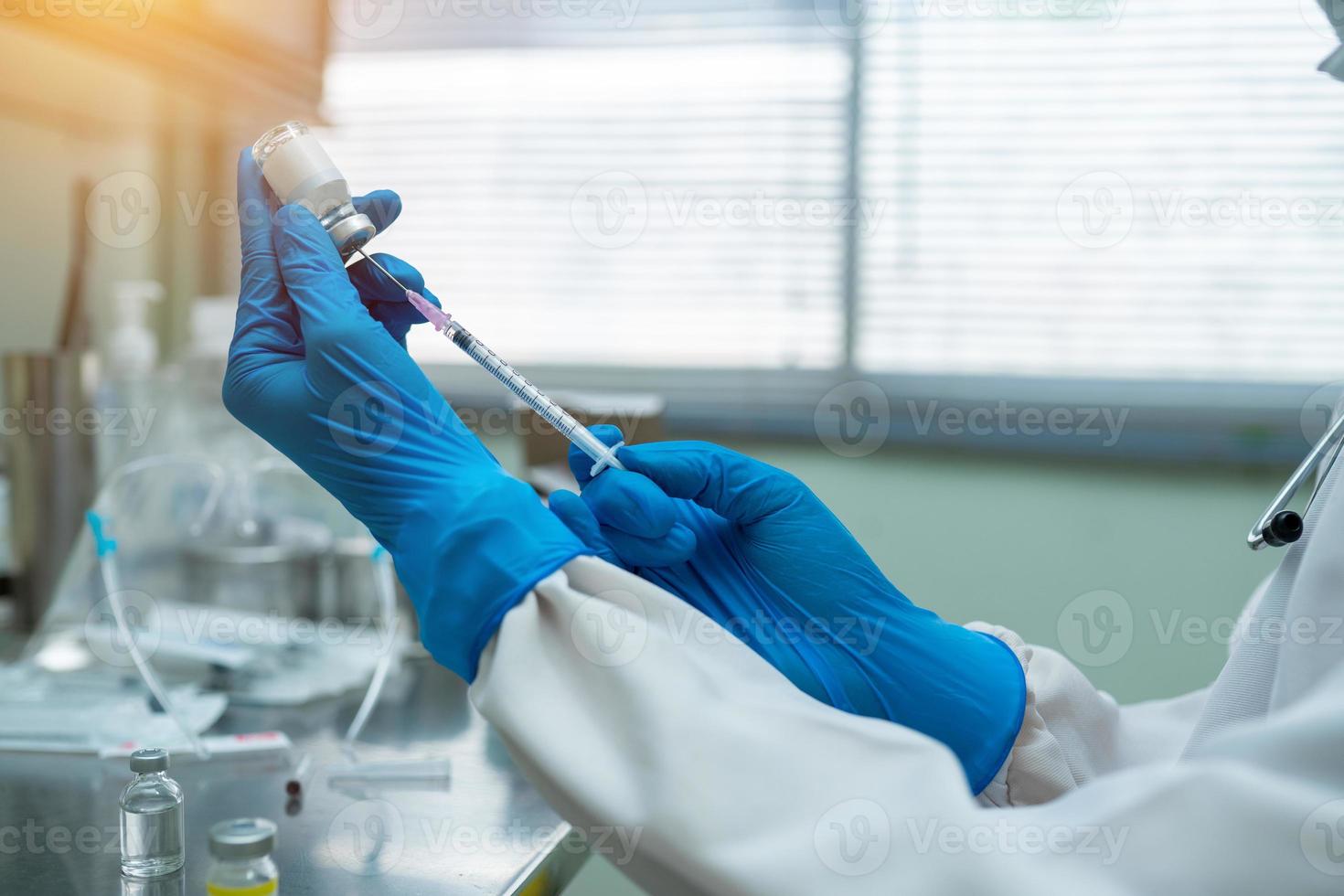 Feche as mãos do médico segurando uma seringa para desenhar a droga da vacina foto