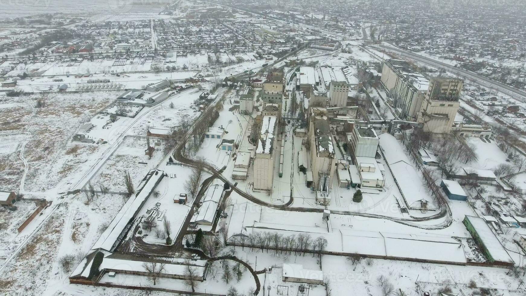 grão terminal dentro a inverno temporada. coberto de neve grão elevador dentro rural áreas. uma construção para secagem e armazenando grão. foto