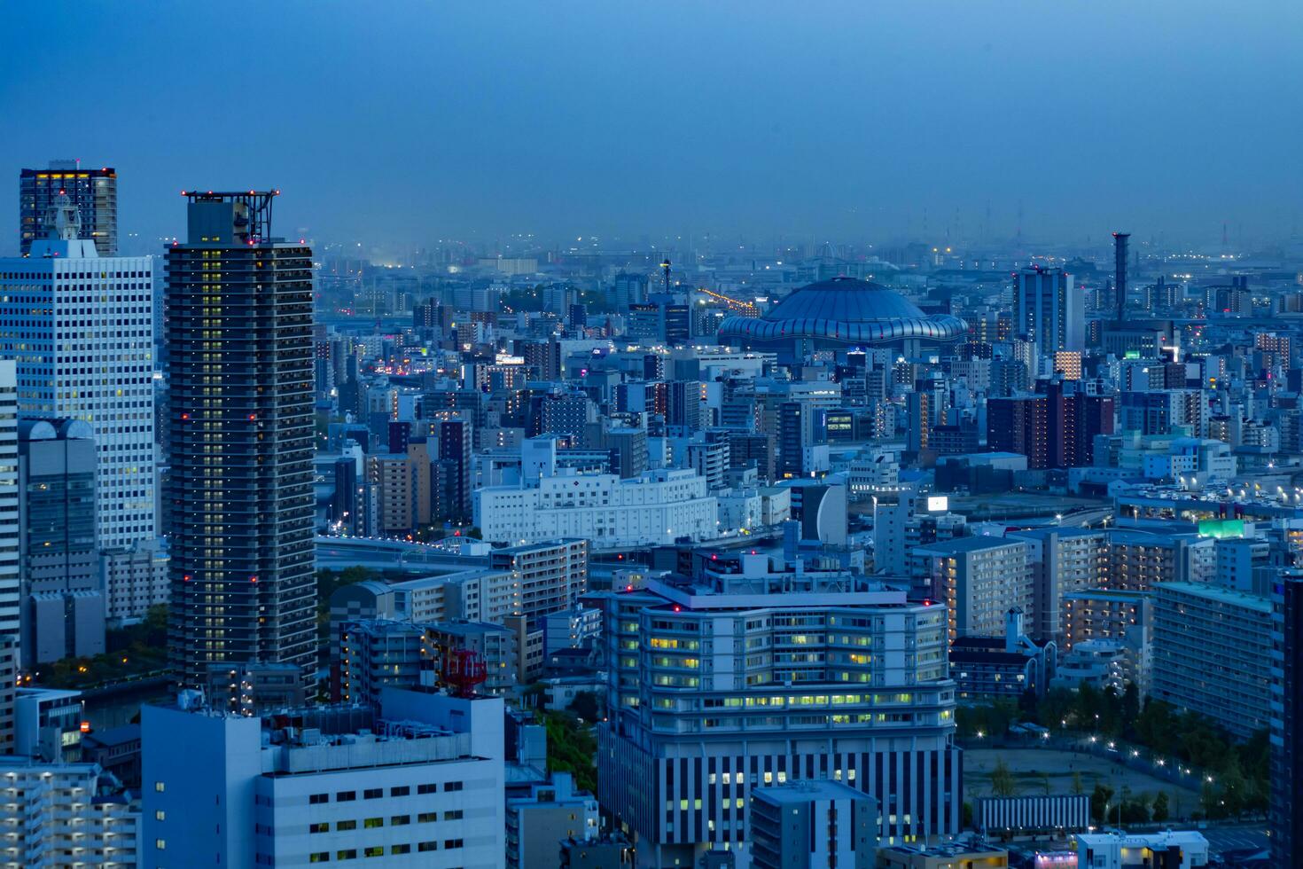 uma crepúsculo paisagem urbana de Alto ângulo Visão perto Kyocera cúpula dentro Osaka foto