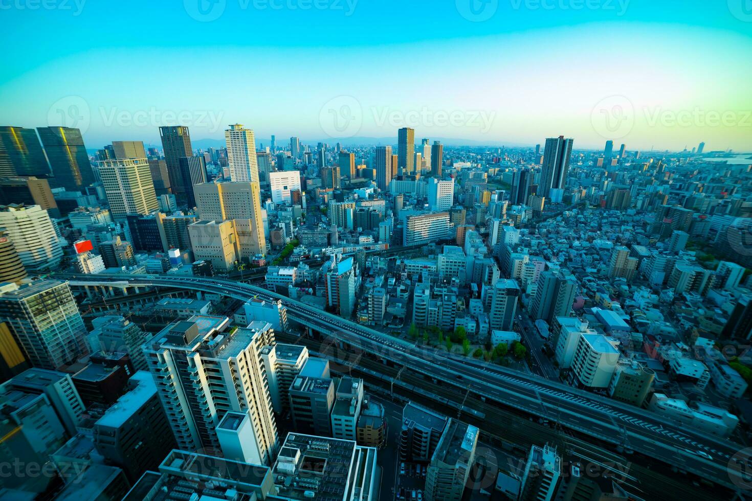 uma crepúsculo panorama paisagem urbana perto a estrada de ferro dentro Osaka Largo tiro foto