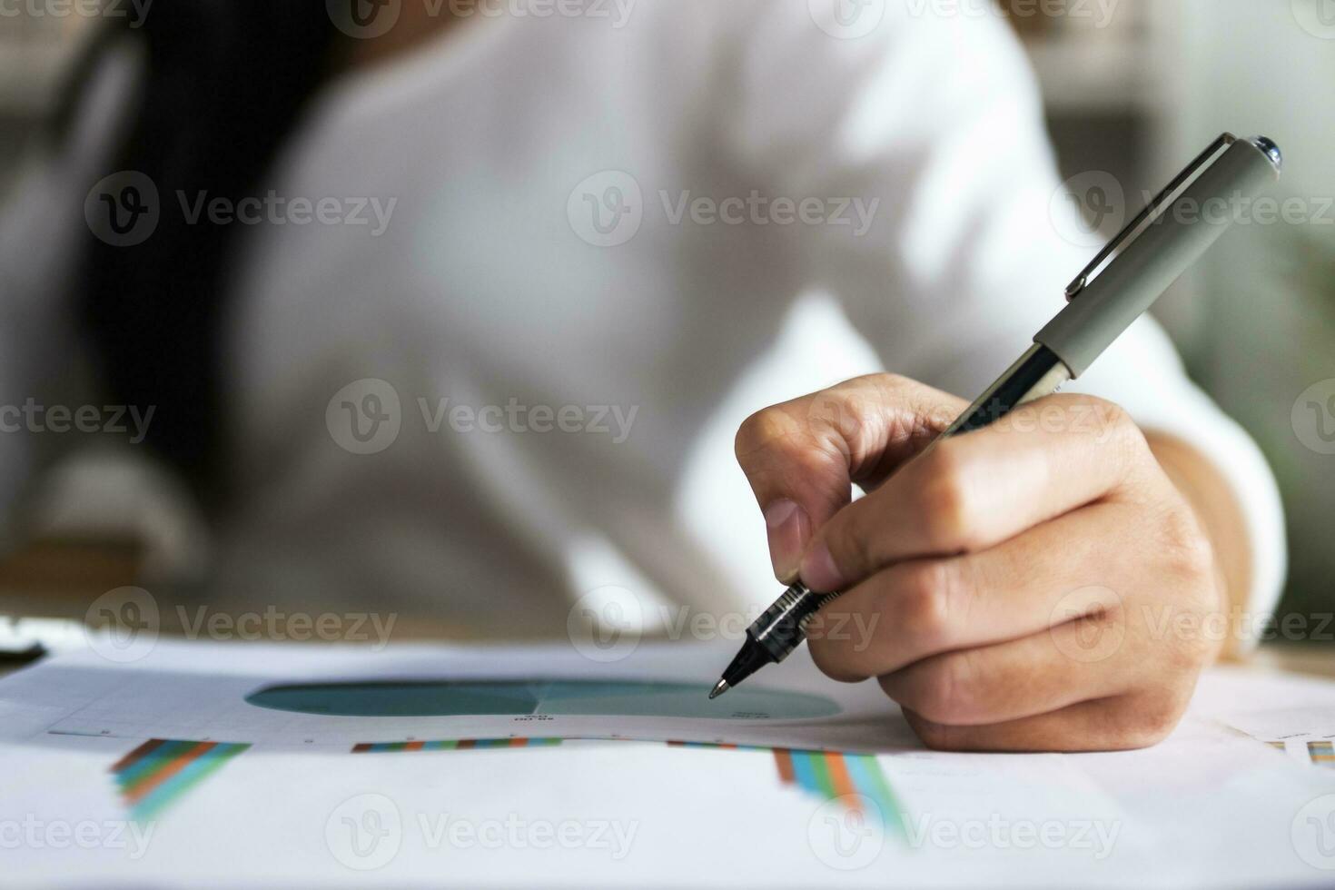 mão do mulher segurando caneta com escrevendo em papel relatório dentro escritório foto