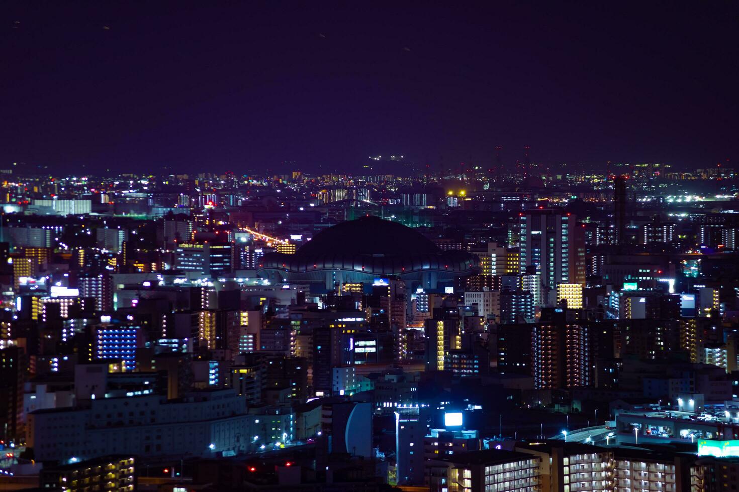 uma noite paisagem urbana de Alto ângulo Visão perto Kyocera cúpula dentro Osaka telefoto tiro foto