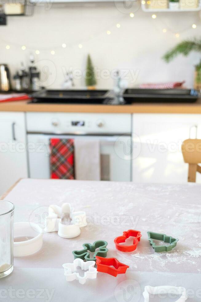 disposição do bolacha cortadores fechar-se cortar Fora biscoitos a partir de a massa com Bolores em uma Natal tema dentro a Formato do uma boneco de neve, uma Natal árvore, estrelas dentro a cozinha foto