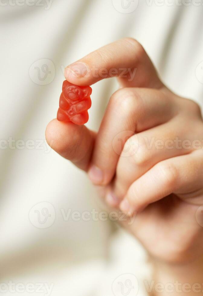 uma menina detém uma gomoso Urso vitaminas dentro dela mãos foto