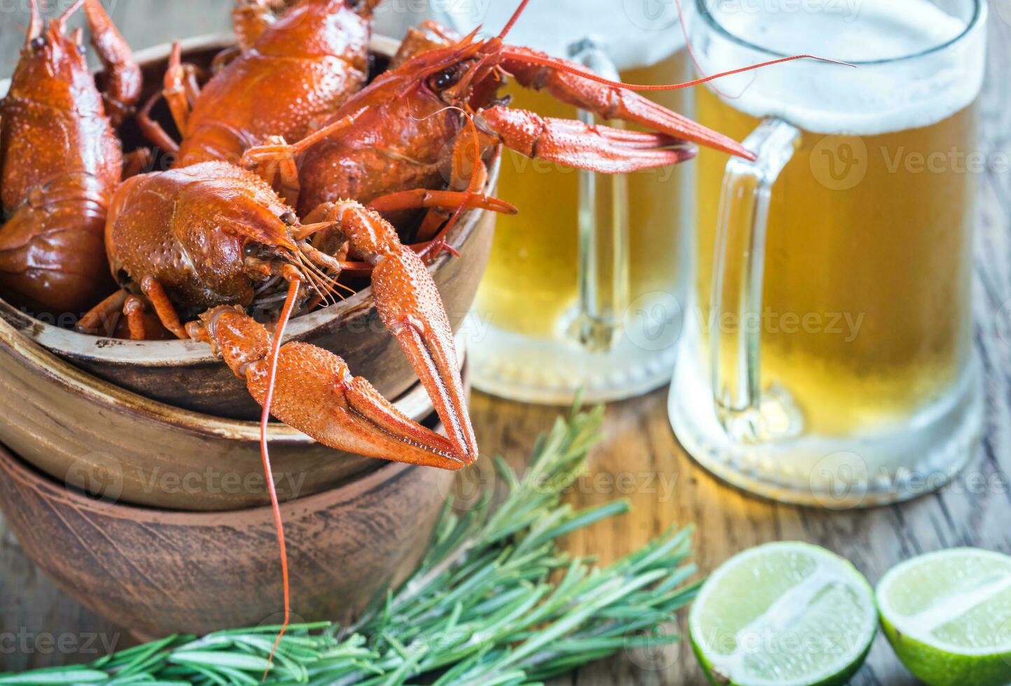 tigela do fervido lagostim com dois canecas do Cerveja foto