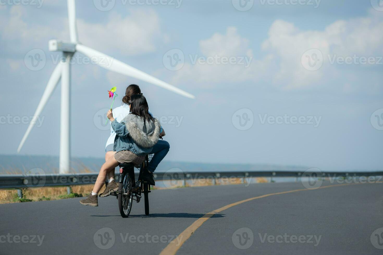 costas Visão do uma jovem mulher equitação uma bicicleta com dela namorado em a estrada foto